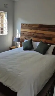 a bedroom with a large white bed with a wooden headboard at Jenkins Re-Treat in Pretoria