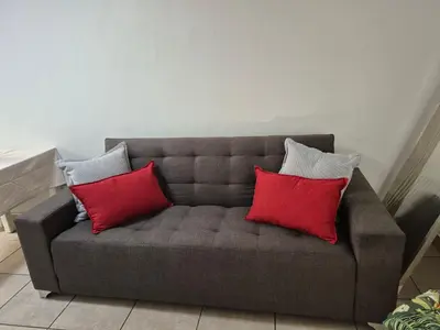 a gray couch with three red pillows on it at Jenkins Re-Treat in Pretoria
