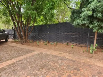 a brick retaining wall with a tree and a fence at Jenkins Re-Treat in Pretoria