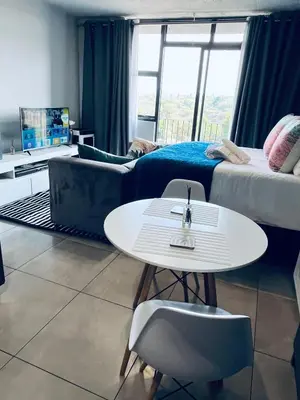 a room with a bed and a table and a couch at The 210 Circa Pretoria Studio in Pretoria