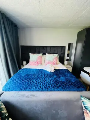 a bedroom with a large blue bed with pink pillows at The 210 Circa Pretoria Studio in Pretoria
