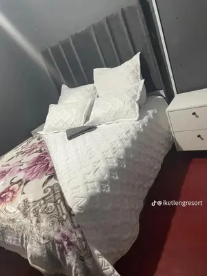 a bed with white sheets and pillows on it at Iketleng Guest House & Resort