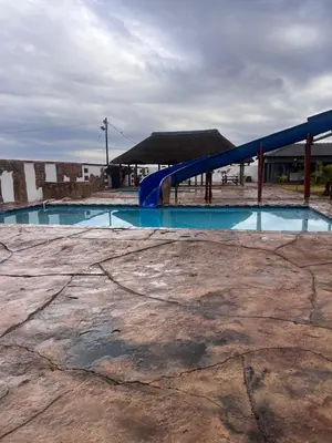 an empty swimming pool with a blue slide at Iketleng Guest House & Resort