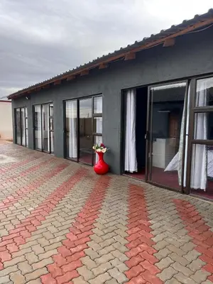 a building with a red vase with flowers in it at Iketleng Guest House & Resort