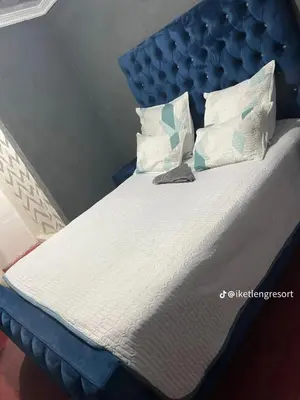 a bed with a blue headboard and white sheets and pillows at Iketleng Guest House & Resort