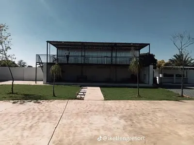 a house with a balcony and palm trees in front of it at Iketleng Guest House & Resort