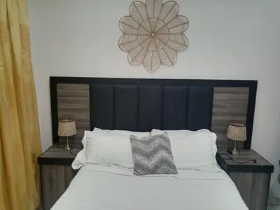 a bed with a black headboard and two tables with lamps at M and E Lodge in Enkelbosch