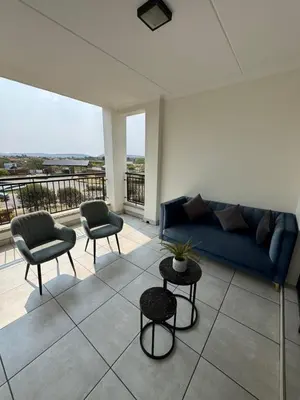 a living room with a blue couch and two chairs at Penthouse On Tropical - The Blyde in Pretoria