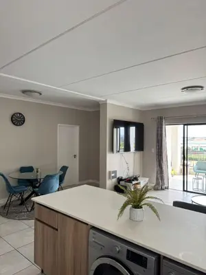 a kitchen and living room with a table and chairs at Penthouse On Tropical - The Blyde in Pretoria