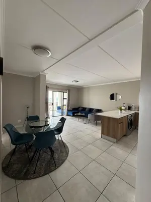 a living room with a table and chairs and a kitchen at Penthouse On Tropical - The Blyde in Pretoria