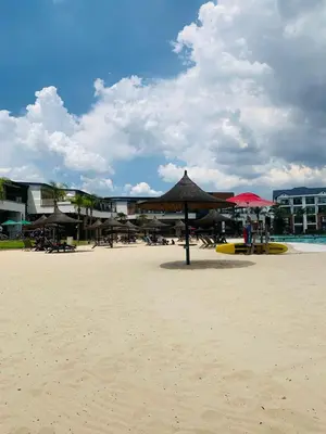 a beach with umbrellas and chairs on the sand at Penthouse On Tropical - The Blyde in Pretoria