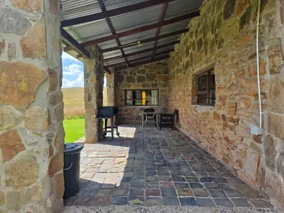 a stone house with a stone wall and a patio at Treeferns Trout Lodge in Dullstroom