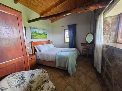 a bedroom with a bed and a table and a mirror at Treeferns Trout Lodge in Dullstroom
