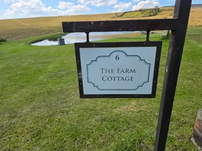 a sign for the farm cottage in a field at Treeferns Trout Lodge in Dullstroom