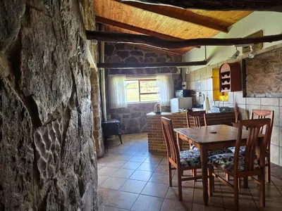 a dining room with a wooden table and chairs at Treeferns Trout Lodge in Dullstroom