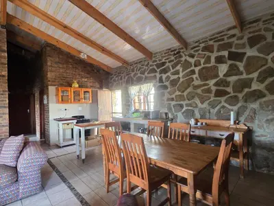 a kitchen with a wooden table and a stone wall at Treeferns Trout Lodge in Dullstroom