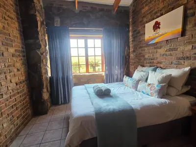 a bedroom with a large bed in a brick wall at Treeferns Trout Lodge in Dullstroom