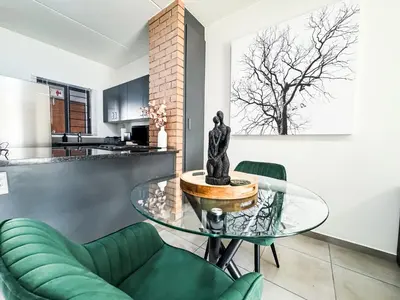 a living room with a glass table and green chairs at Executive Apartment at Waterfall Ridge in Midrand