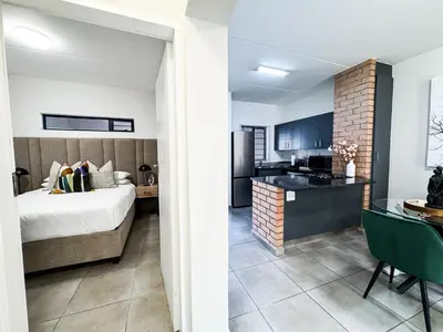 a bedroom with a bed and a kitchen in a room at Executive Apartment at Waterfall Ridge in Midrand