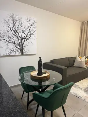 a living room with a couch and a table and chairs at Executive Apartment at Waterfall Ridge in Midrand