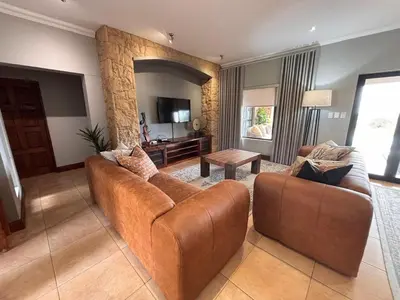a living room with a brown couch and a table at Euphoria Self Catering Home in Naboomspruit
