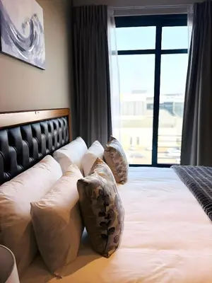a bedroom with a bed with pillows and a window at Menlyn Maine Residences - Capital Trilogy in Pretoria