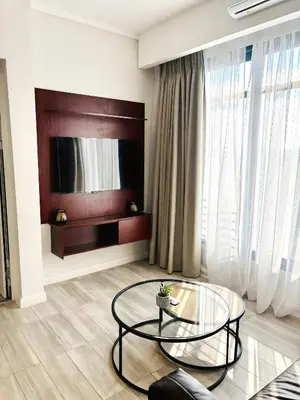 a living room with a glass table and a tv at Menlyn Maine Residences - Capital Trilogy in Pretoria