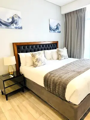 a bedroom with a large bed with a black headboard at Menlyn Maine Residences - Capital Trilogy in Pretoria