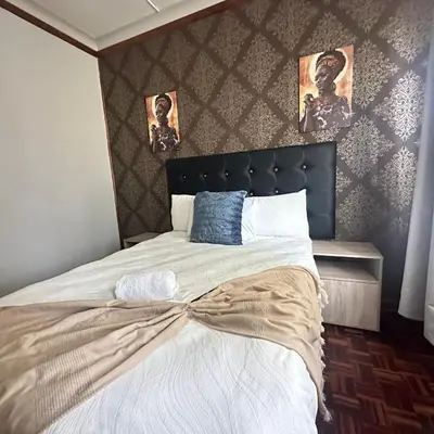 a bedroom with a large bed with a headboard at MBT Lodge in Polokwane