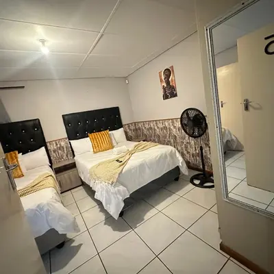 a bedroom with two beds and a mirror at MBT Lodge in Polokwane