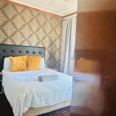 a bedroom with a bed with yellow pillows at MBT Lodge in Polokwane