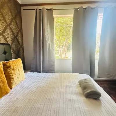 a bedroom with a white bed with a window at MBT Lodge in Polokwane