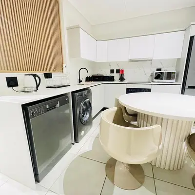 a white kitchen with a table and a dishwasher at The Blyde Crystal lagoon in Pretoria