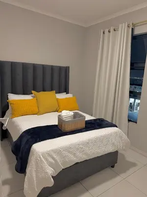 a bed with yellow pillows and a gray headboard at Charlsi luxury in Midrand