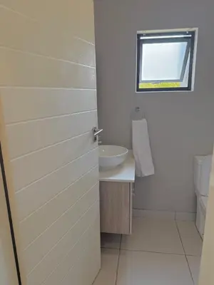 a bathroom with a sink and a toilet and a door at Charlsi luxury in Midrand