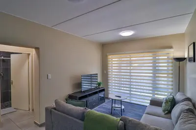a living room with a couch and a piano at Waterfall Ridge Luxurious Apartments - Backup Power! in Midrand