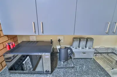 a kitchen with a counter with a stove and a microwave at Waterfall Ridge Luxurious Apartments - Backup Power! in Midrand