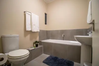 a bathroom with a toilet and a tub and a sink at Waterfall Ridge Luxurious Apartments - Backup Power! in Midrand