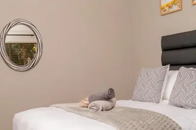 a bedroom with a white bed with a round mirror at SinoVilla397 in Pretoria