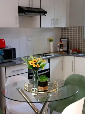 a kitchen with a glass table with a vase of flowers at SinoVilla397 in Pretoria