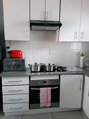 a kitchen with white cabinets and a stove with pots and pans at SinoVilla397 in Pretoria