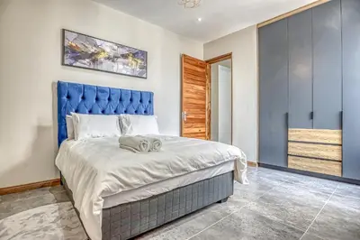 a bedroom with a large bed with a blue headboard at The Waterkloof Gables in Pretoria