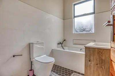 a bathroom with a toilet and a tub and a window at The Waterkloof Gables in Pretoria