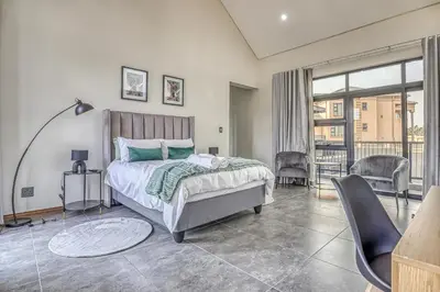 a bedroom with a bed and a table and chairs at The Waterkloof Gables in Pretoria