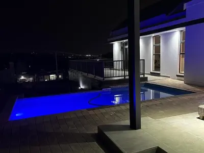 a swimming pool at night with a house at The Waterkloof Gables in Pretoria