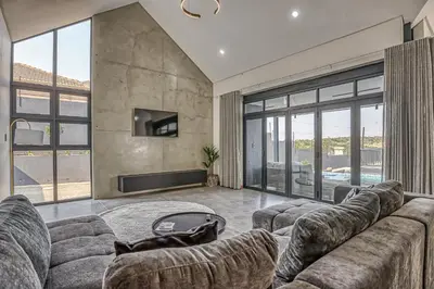 a living room with a large couch and a tv at The Waterkloof Gables in Pretoria