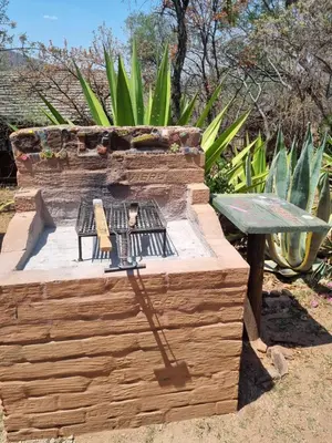 a wooden fire pit with two chairs and a table at Pumba's Den Kranspoort in Winterkamp