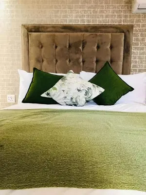 a bed with green and white sheets and pillows at Makhasana