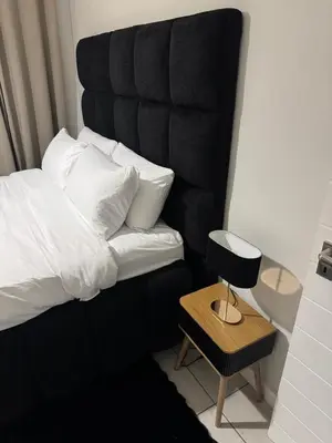 a bed with a black headboard and a table with a lamp at The Dream Stay At The Blyde - Suite 3 in Pretoria