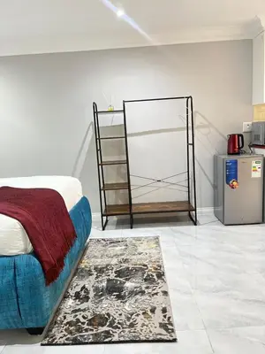 a bedroom with a bed and a rug and a refrigerator at The Airport Terminal Guesthouse in Kempton Park